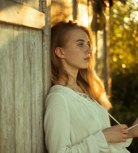 Woman Wearing White Top Leaning on Wooden Wall