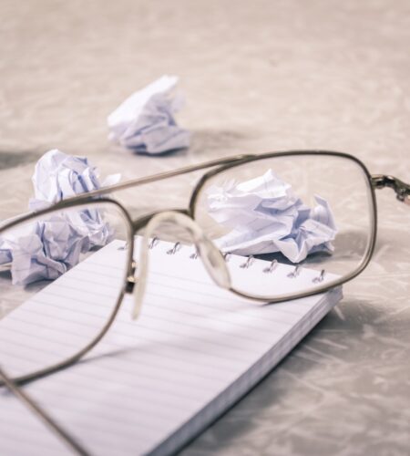 Close-Up Photography of Eyeglasses Near Crumpled Papers