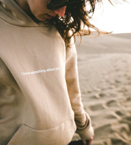 person wearing sunglasses and hoodie on sand