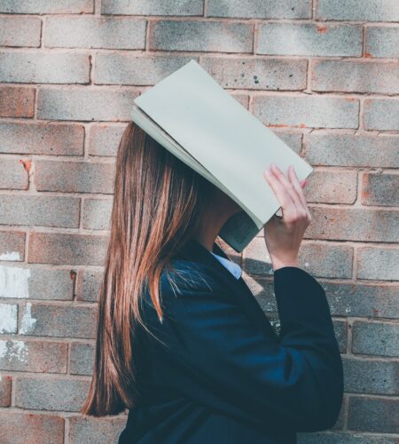 woman covering her face with an open book