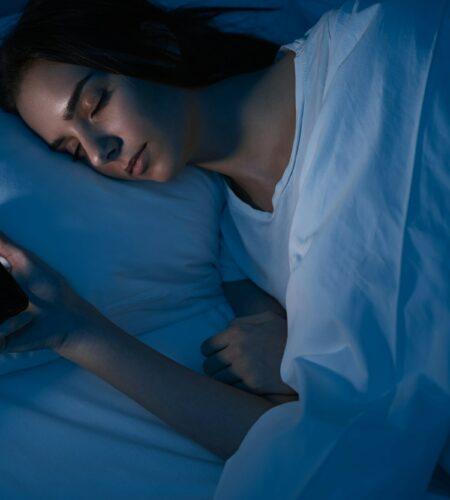 Woman sleeping with smartphone in bed