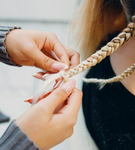 Hairstylist braided afro braids pigtails hair of female client in barber salon