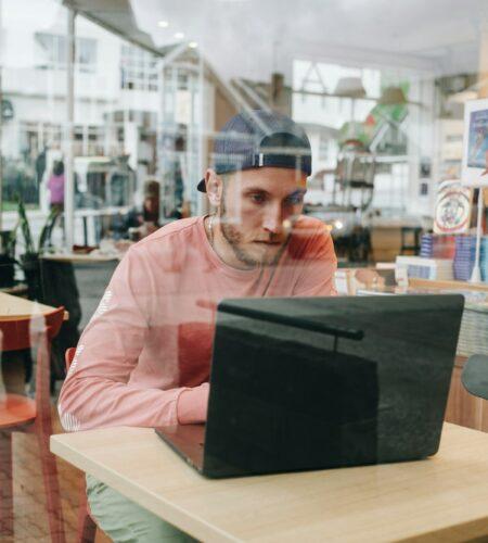 Man work on laptop in cafe window